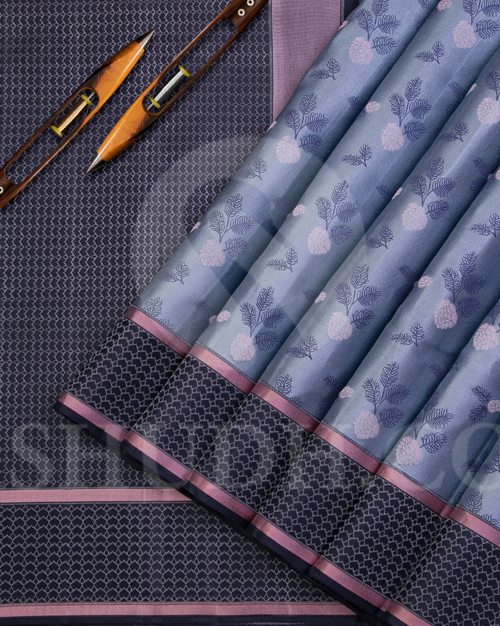 Youthful & Fresh, this Stunning Kanjivaram Silk Saree is out of the ordinary. The pleasing light grey body is adorned with white flowers and dark grey leaves, giving a soft feel, reminding one of japanese art. The complimenting charcoal grey border and pallu features an attractive satin finish and is adorned with a contemporary geometric pattern woven with gold silver zari. The charcoal grey blouse with matching border looks stunning with the light grey, giving a uber cool look in a Saree.