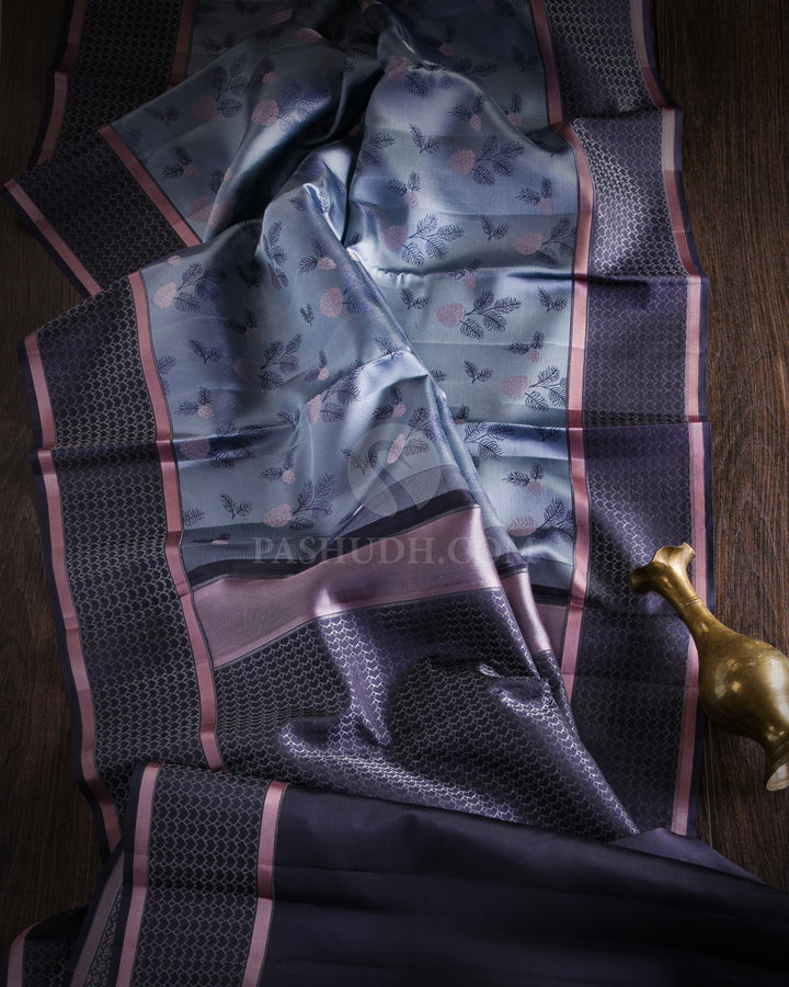 Youthful & Fresh, this Stunning Kanjivaram Silk Saree is out of the ordinary. The pleasing light grey body is adorned with white flowers and dark grey leaves, giving a soft feel, reminding one of japanese art. The complimenting charcoal grey border and pallu features an attractive satin finish and is adorned with a contemporary geometric pattern woven with gold silver zari. The charcoal grey blouse with matching border looks stunning with the light grey, giving a uber cool look in a Saree.